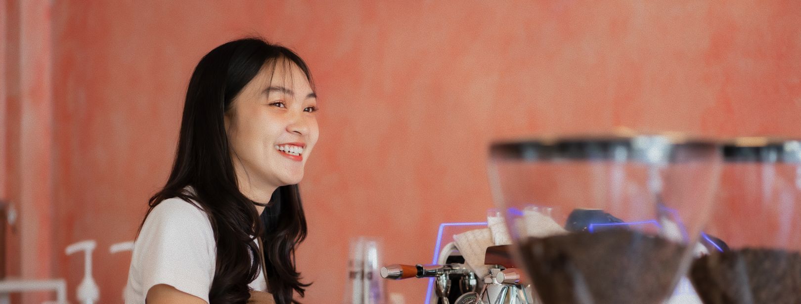 Three young people smiling at the camera outdoors, arms around each other. Sun is shining.