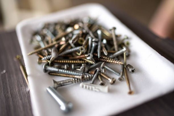 A pile of screws and nails on a white plate on a table.