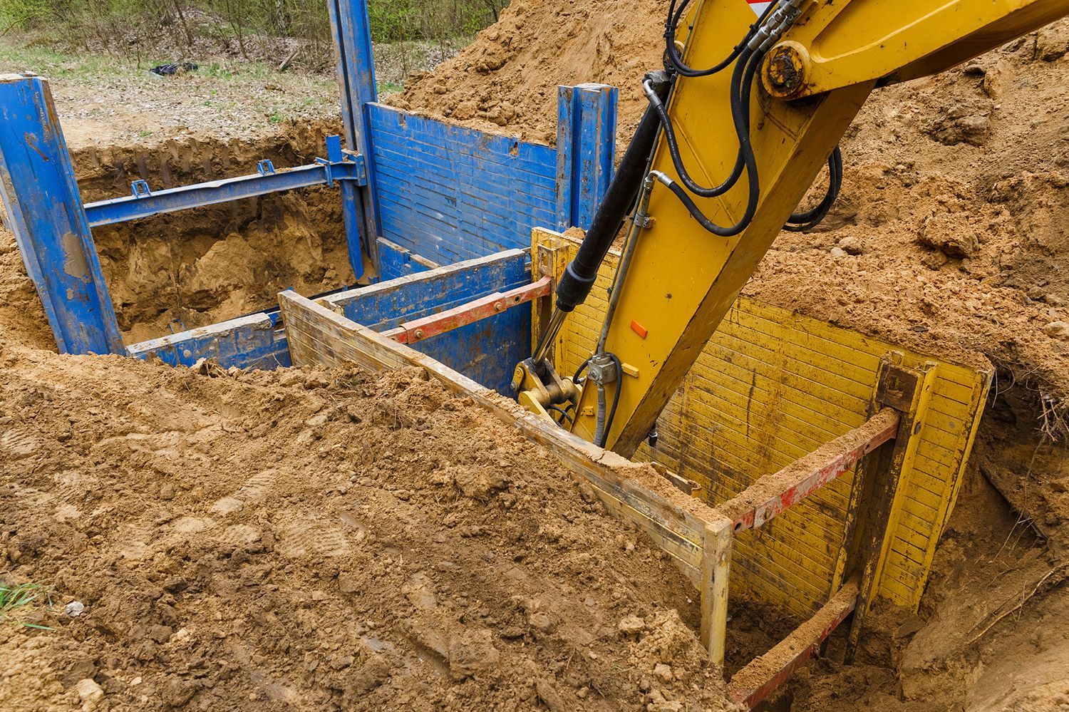 A yellow excavator is digging a hole in the ground.