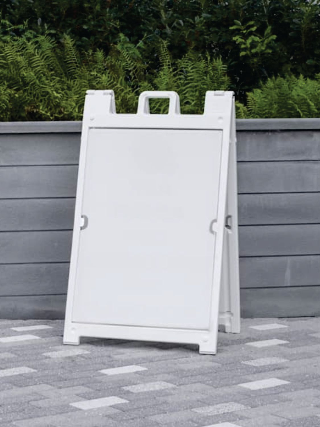 White sandwich board sign on a paved area, ready for display.