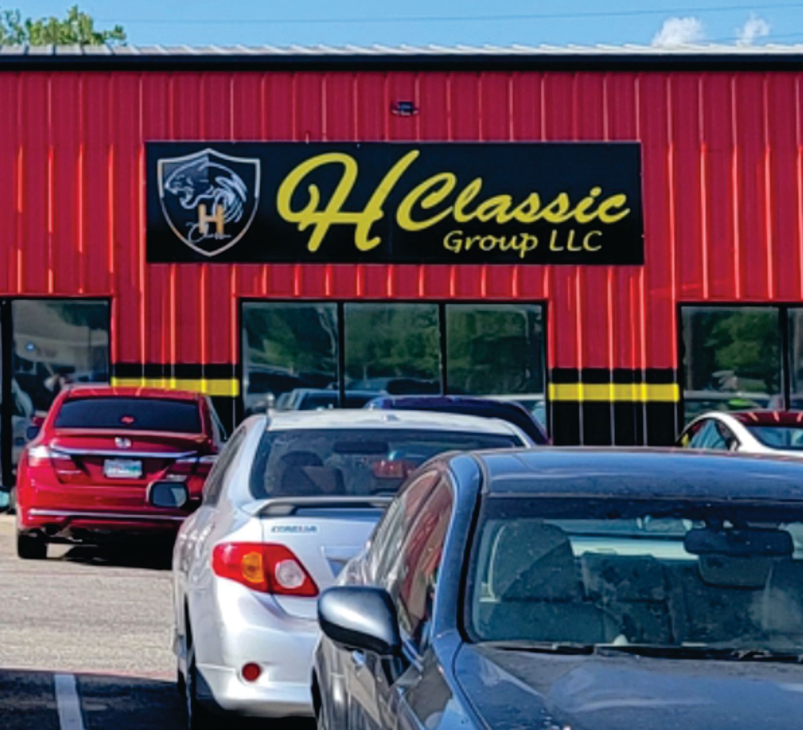 Camp 7 Convenience store with sign, white door, and blue open sign. Building has a tan exterior and blue sky.