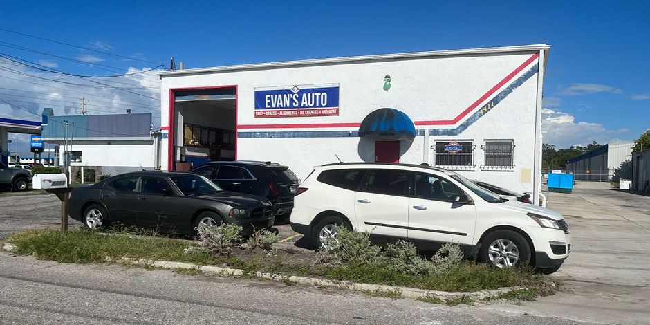 a white suv is parked in front of a car repair shop.