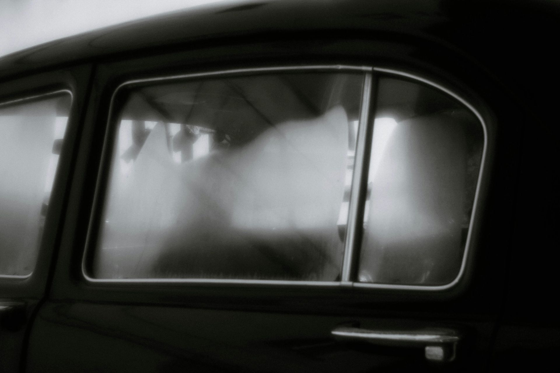 A black and white photo of a car window with smoke coming out of it