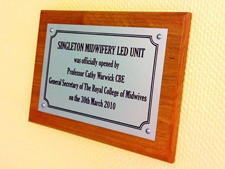 Engraved commemorative plaque mounted on varnished hardwood base