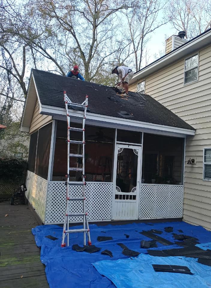 Two roofers replace shingles on a screen porch roof. A ladder stands ready; a blue tarp covers the ground.
