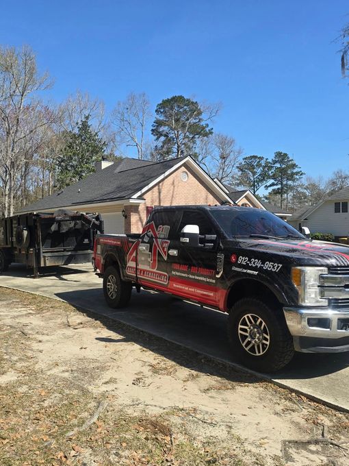 Black truck with red graphics parked in front of a house with a trailer attached; sunny day.