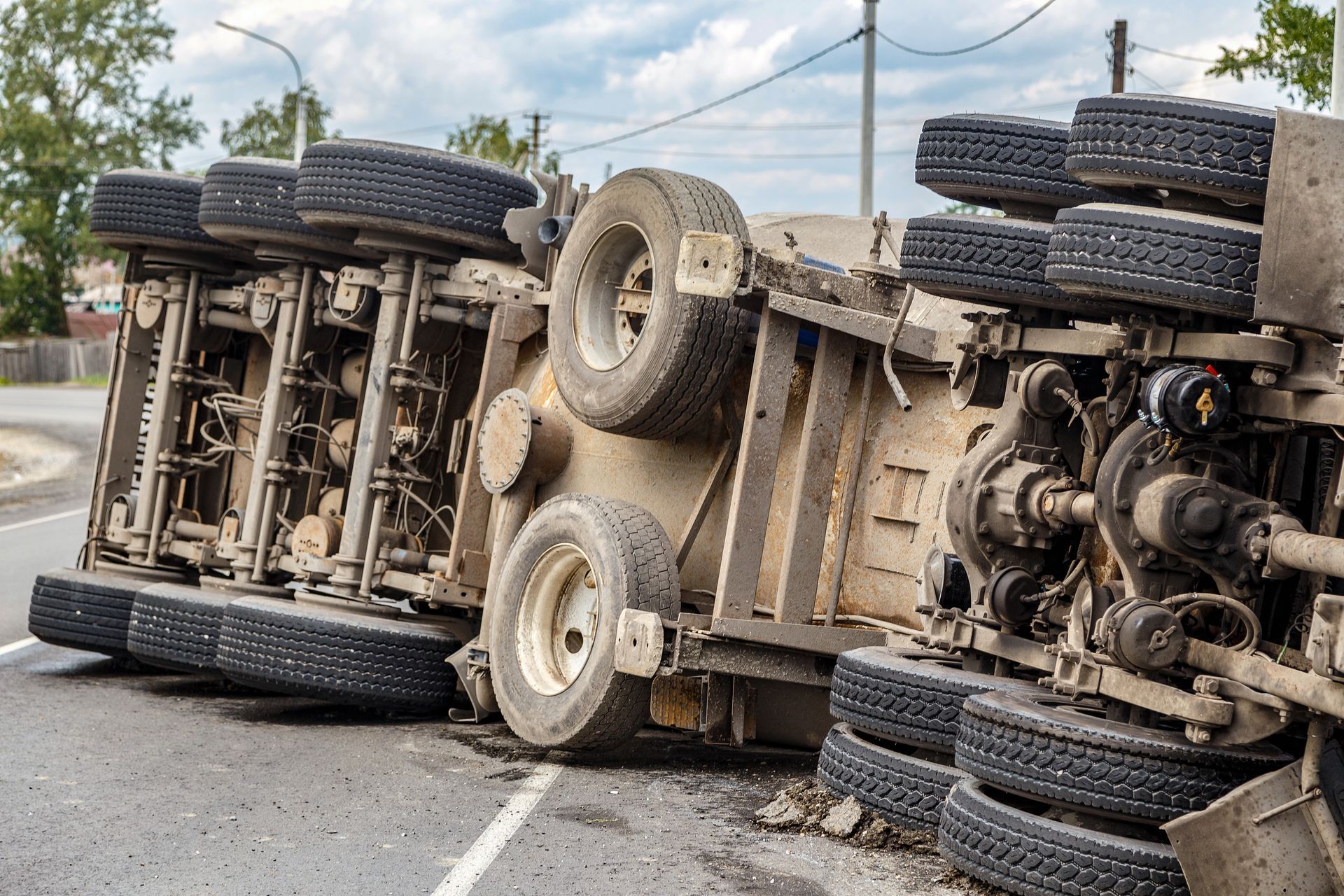 A truck is turned over on its side on the side of the road.
