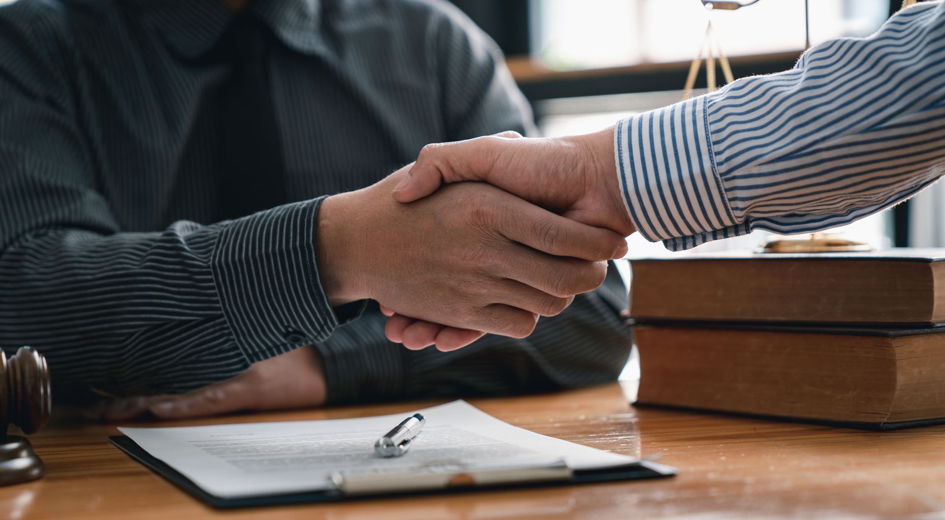 Two men are shaking hands while sitting at a table.