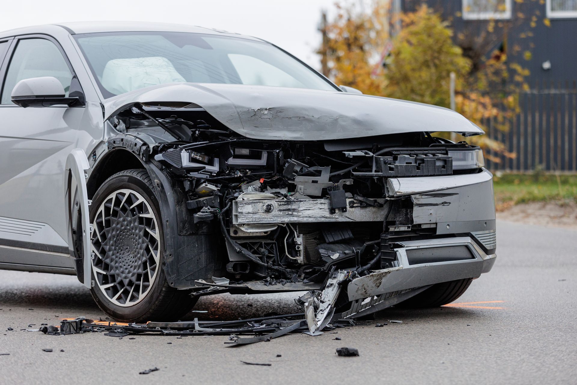 A car with a damaged front end is parked on the side of the road.