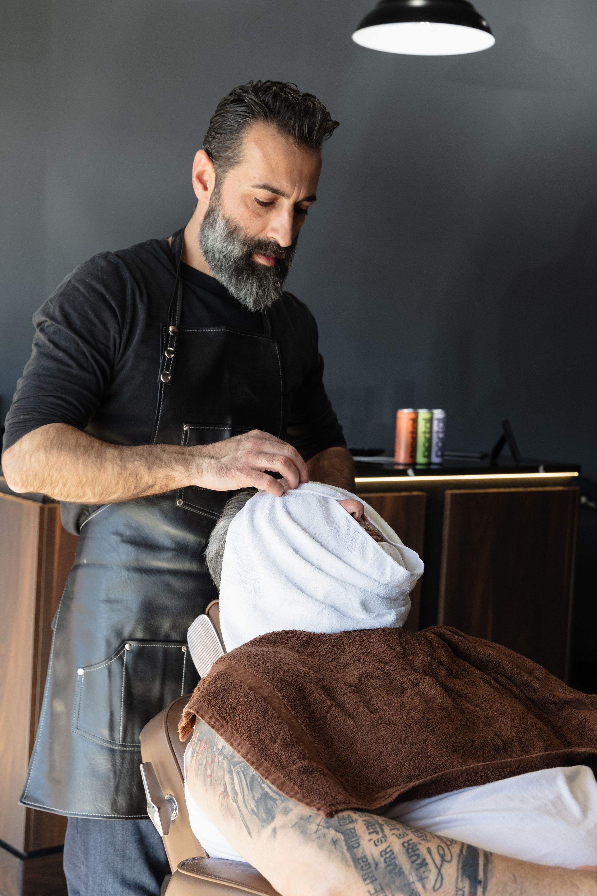 a man with a beard and suspenders is standing in a dark room .