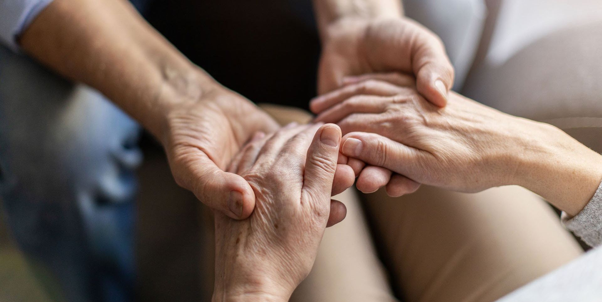 A man and a woman are holding hands while sitting on a couch.