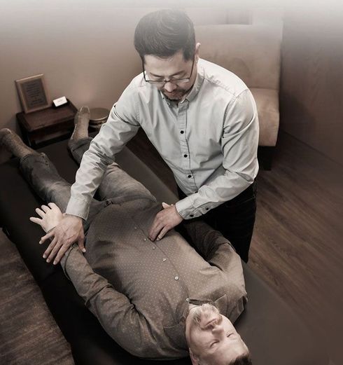 A man is laying on a table getting a massage from another man