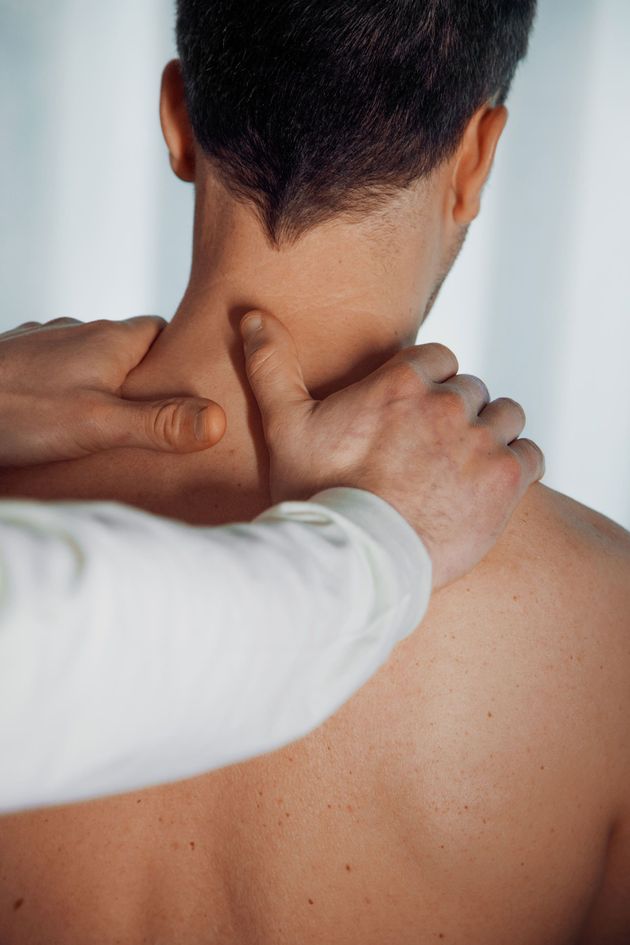 A man is getting a massage on his neck and back.