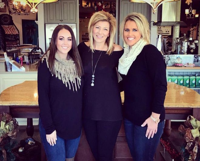 Three women are posing for a picture in a kitchen