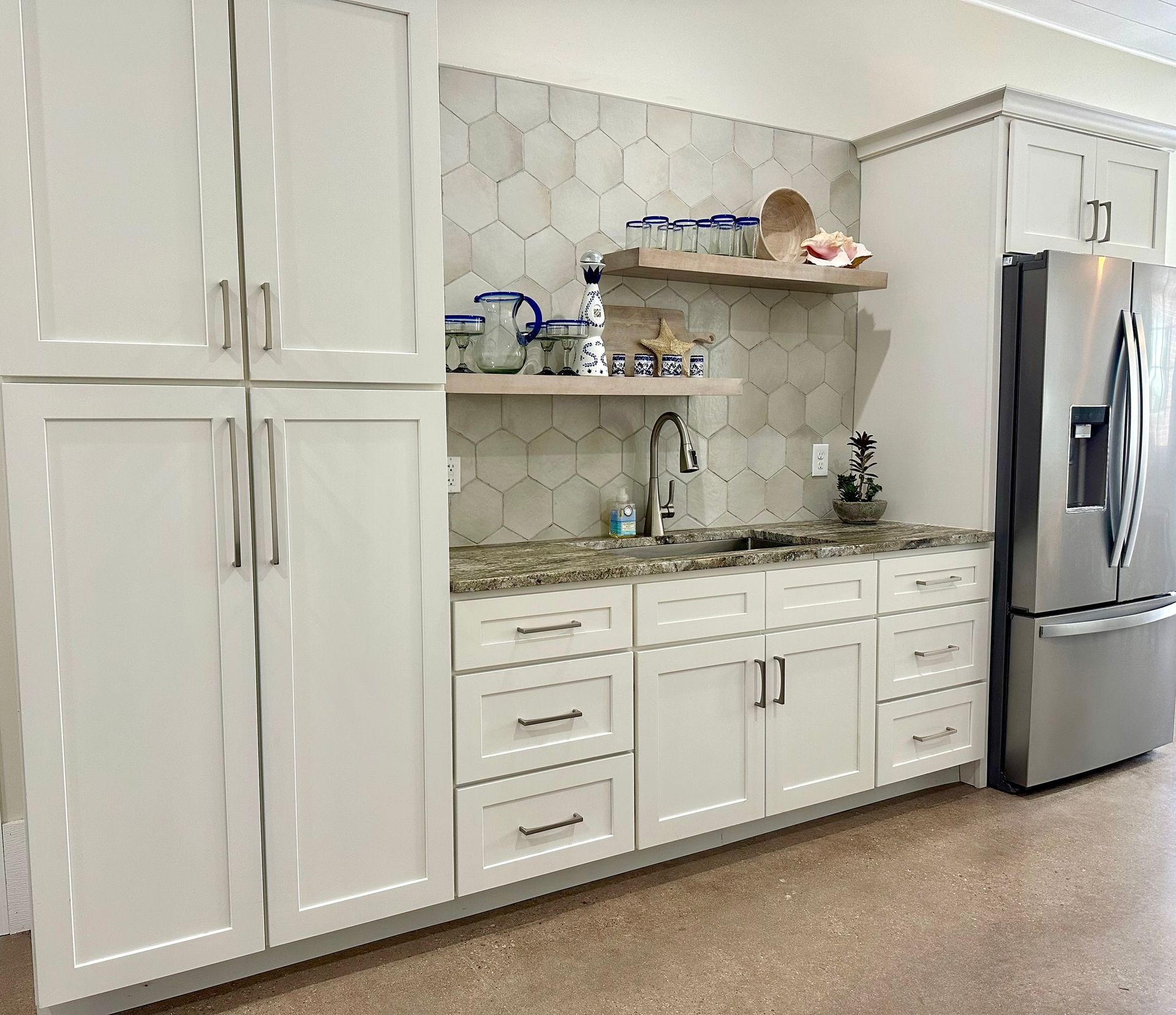 A kitchen with white cabinets and a stainless steel refrigerator