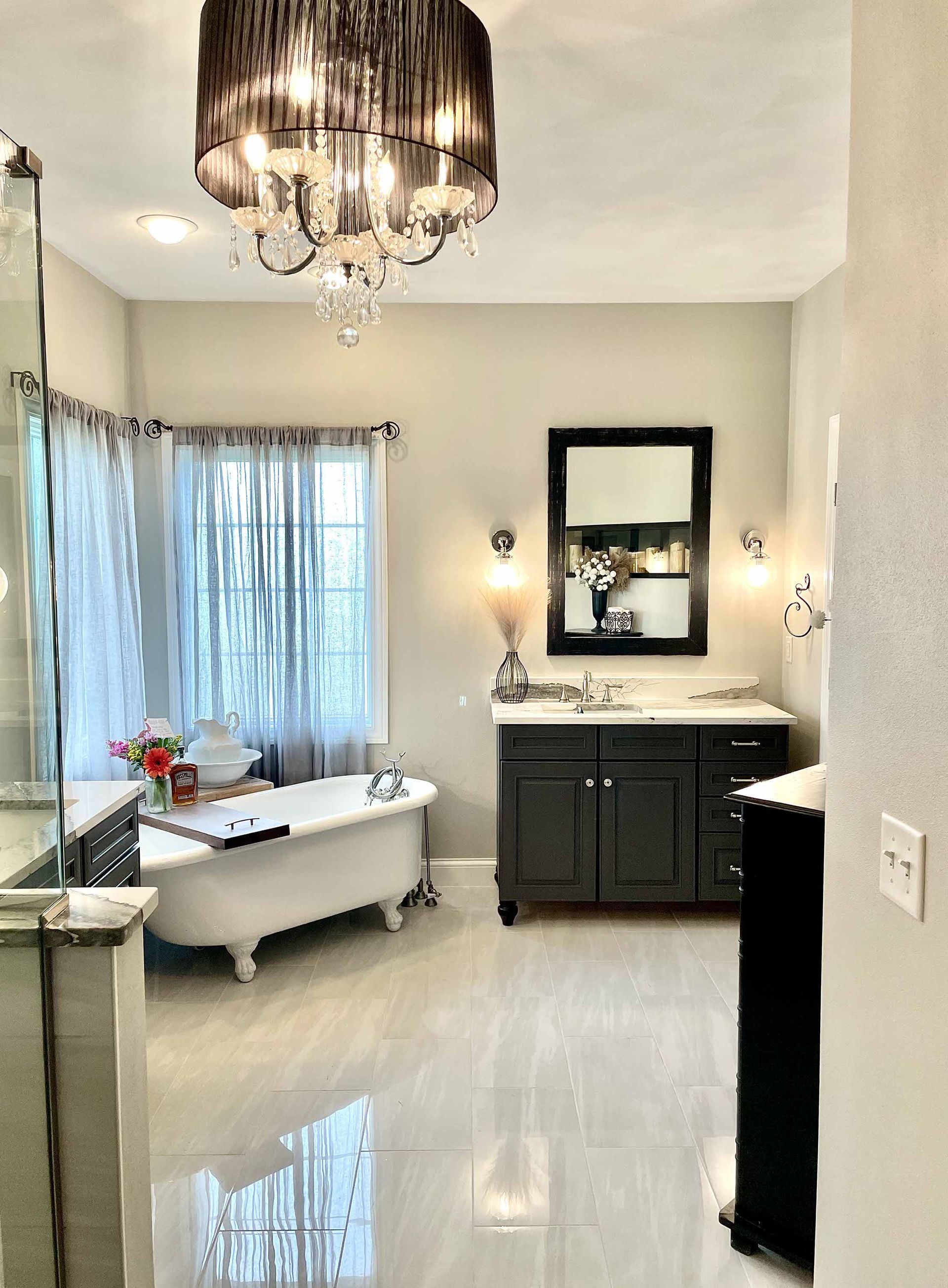 A bathroom with a bathtub , sink , mirror and chandelier.