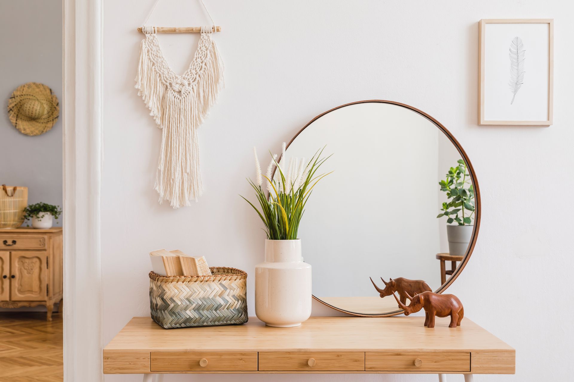 A wooden table with a vase of flowers and a mirror on it.