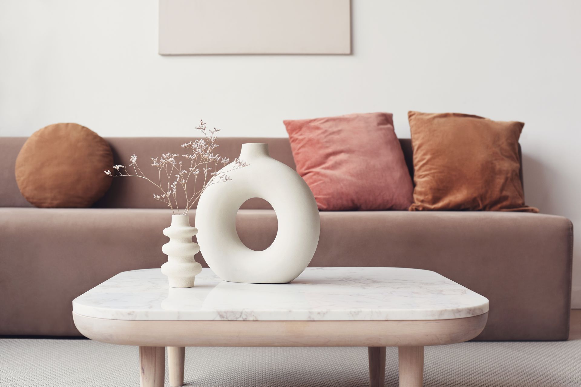 A living room with a couch and a coffee table with vases on it.