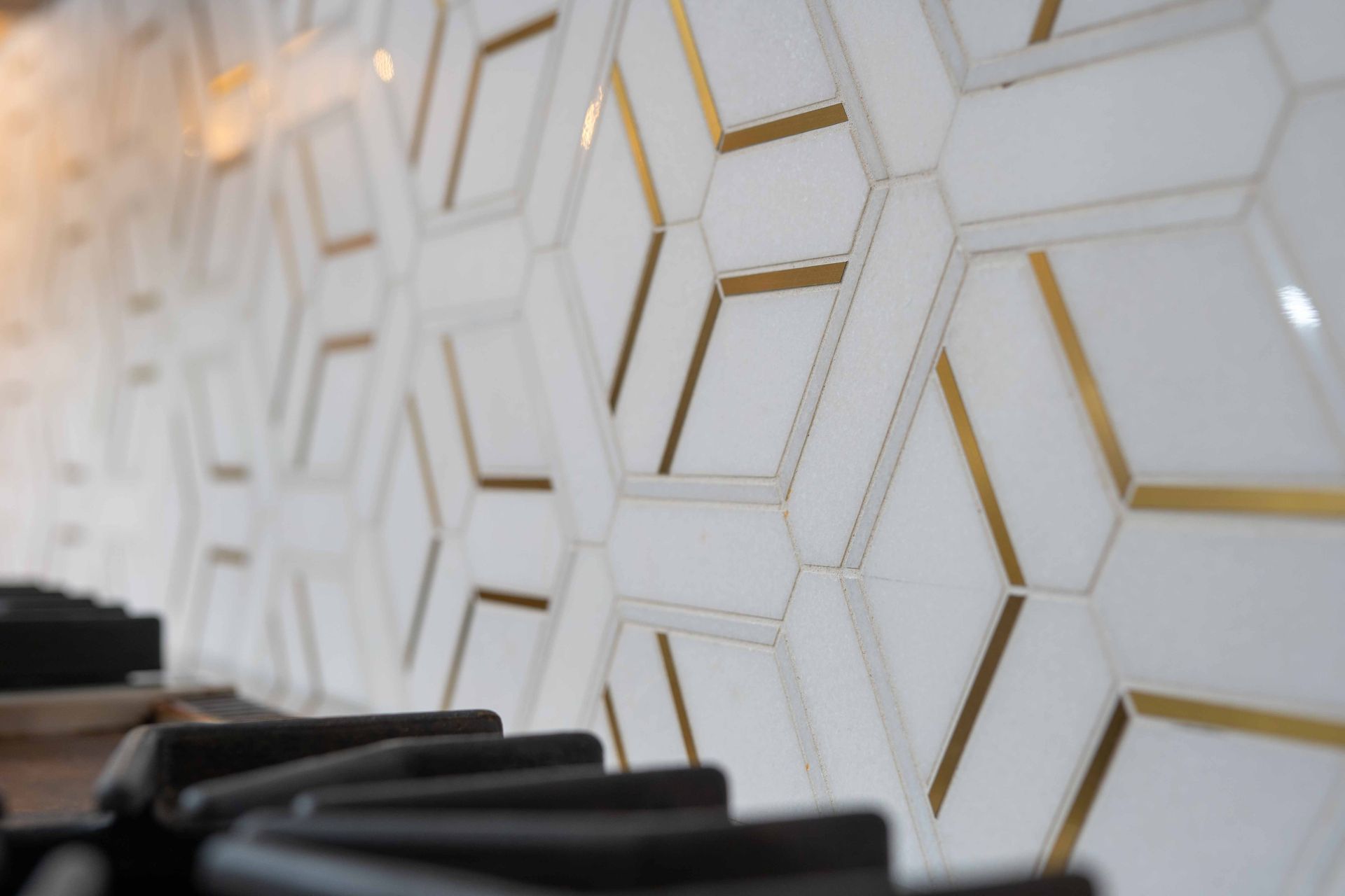 A close up of a stove top oven with a geometric pattern on the wall.