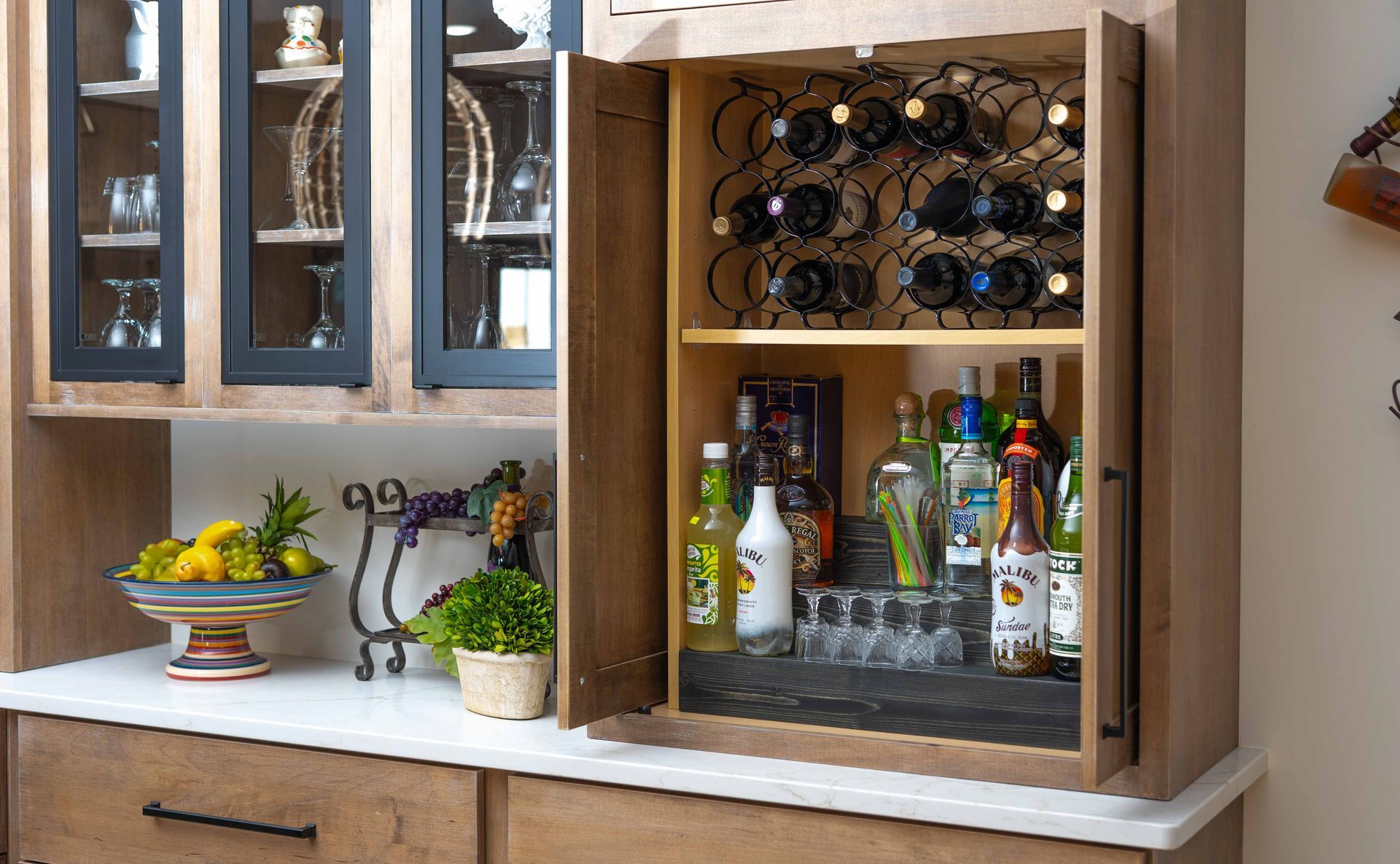 A wine cabinet with bottles and glasses inside of it.