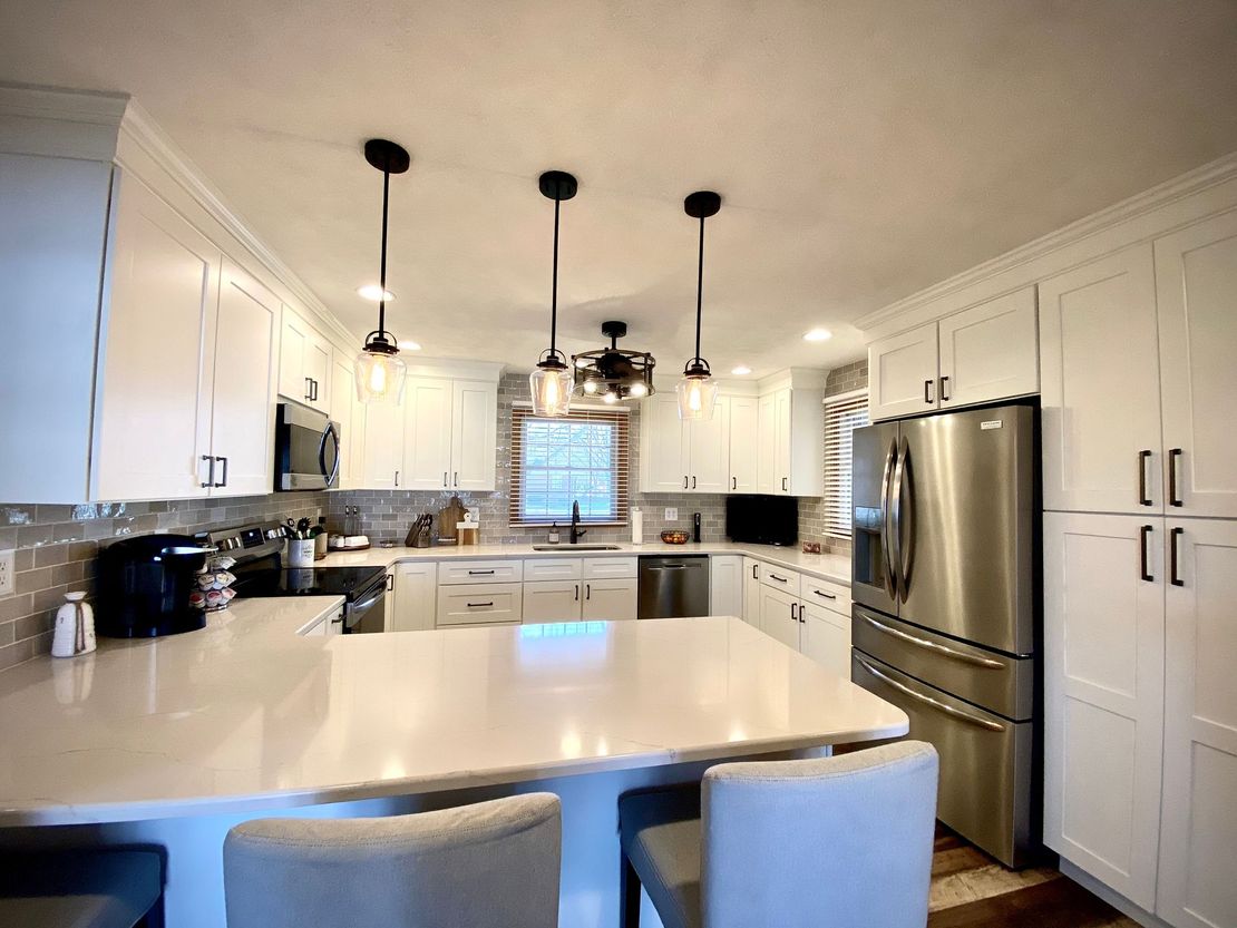 A kitchen with white cabinets , stainless steel appliances , and a large island.