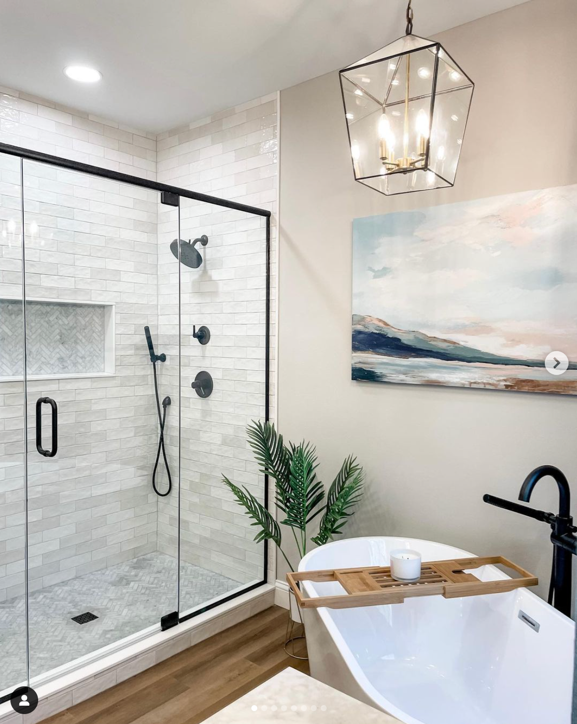 A bathroom with a tub , shower , and painting on the wall.