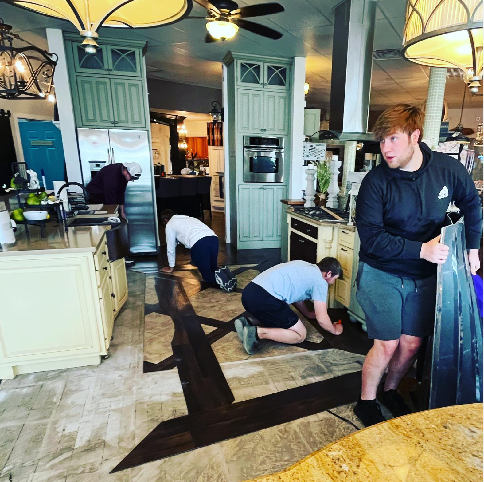 A man is kneeling on the floor in a kitchen