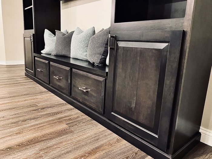 A wooden entertainment center with a bench and drawers