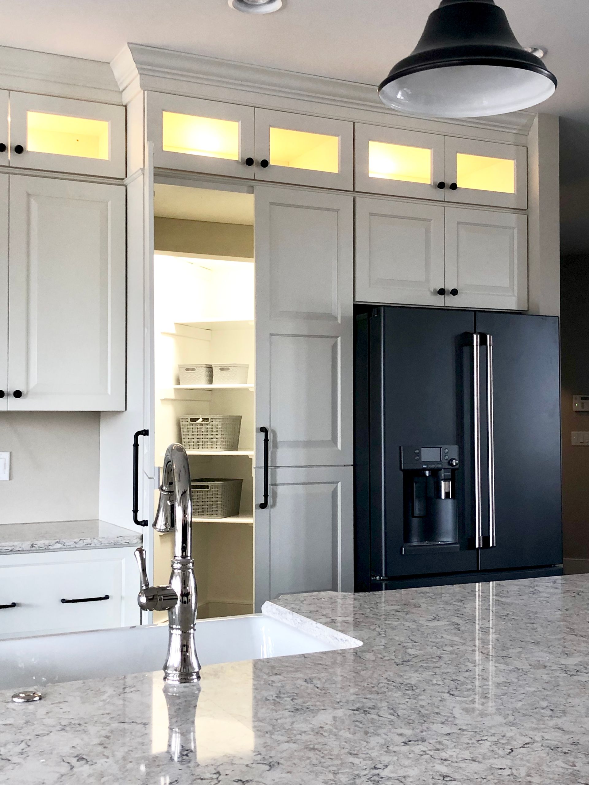 A kitchen with white cabinets and a black refrigerator