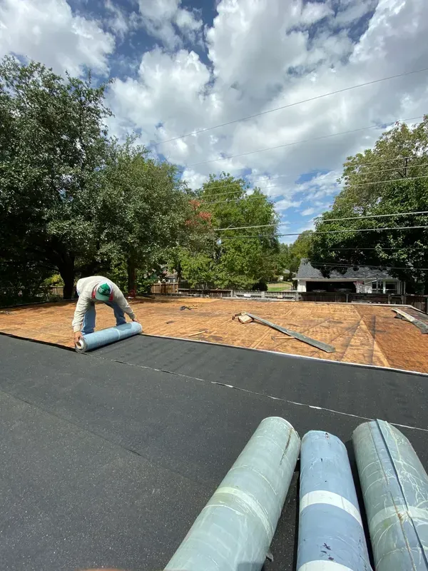 A man is laying a roof on top of a house.
