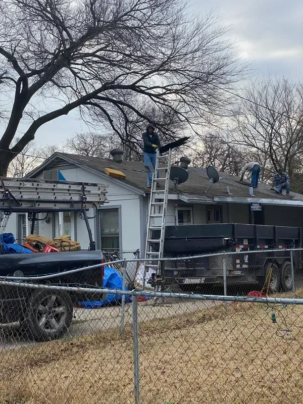 A group of people are working on the roof of a house.