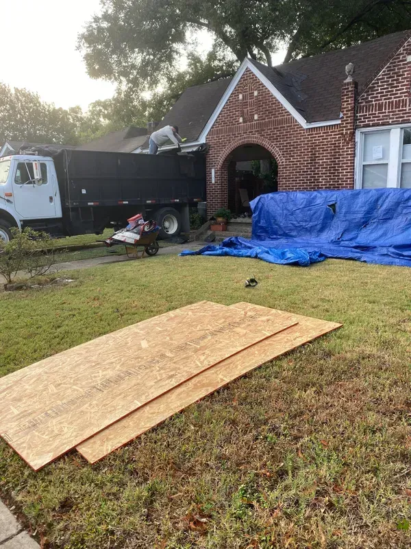 A dump truck is parked in front of a brick house.