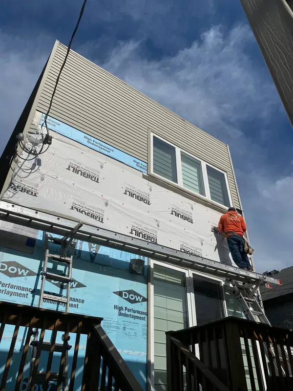A man on a ladder is working on the side of a building