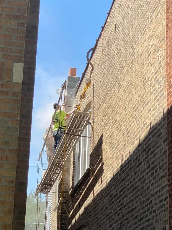 A man is standing on a scaffolding on the side of a building.