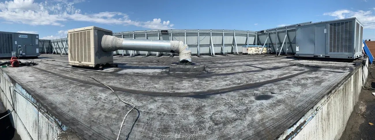 A panoramic view of a roof with a lot of air conditioners on it.