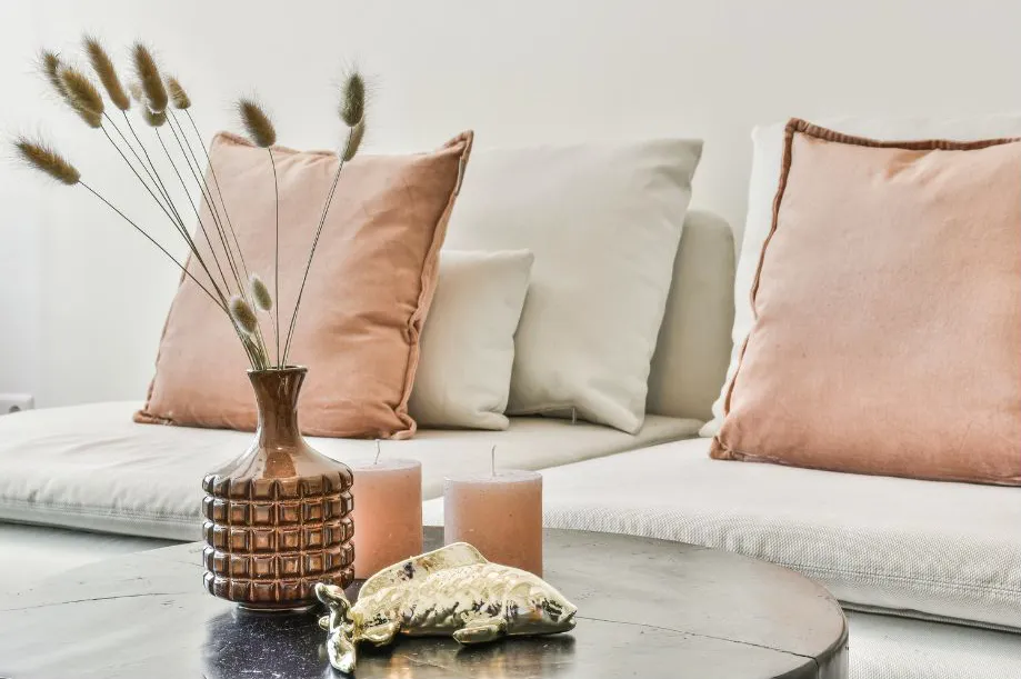 Sofa With Pink and Cream Pillows, Brown Vase With Dried Grass, Candles, and a Decorative Object — Jodi Maree Interiors in Dubbo, NSW