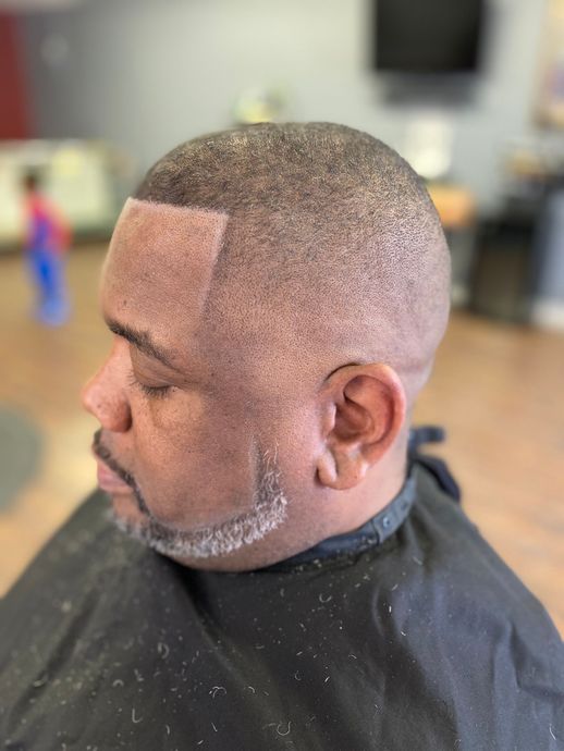 A man is getting his hair cut at a barber shop.