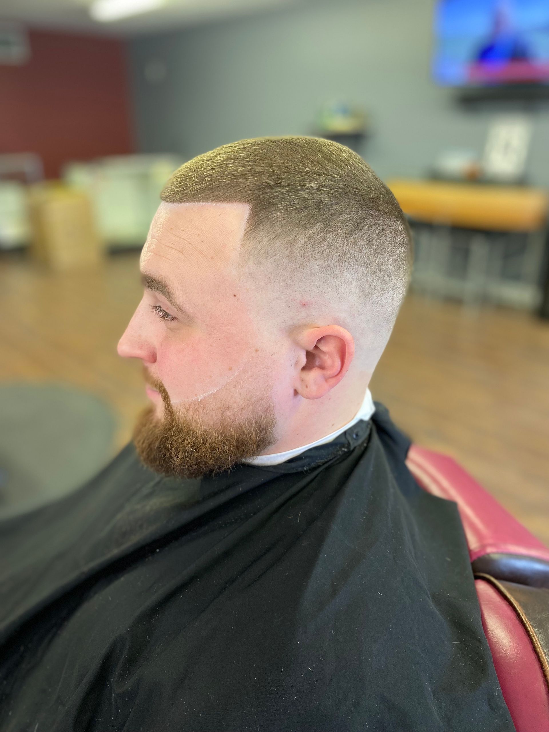 A man with a beard is getting his hair cut at a barber shop.