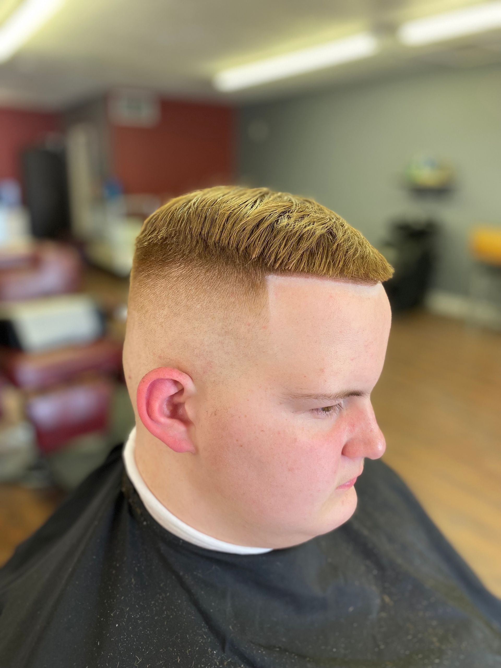 A man is getting his hair cut at a barber shop.