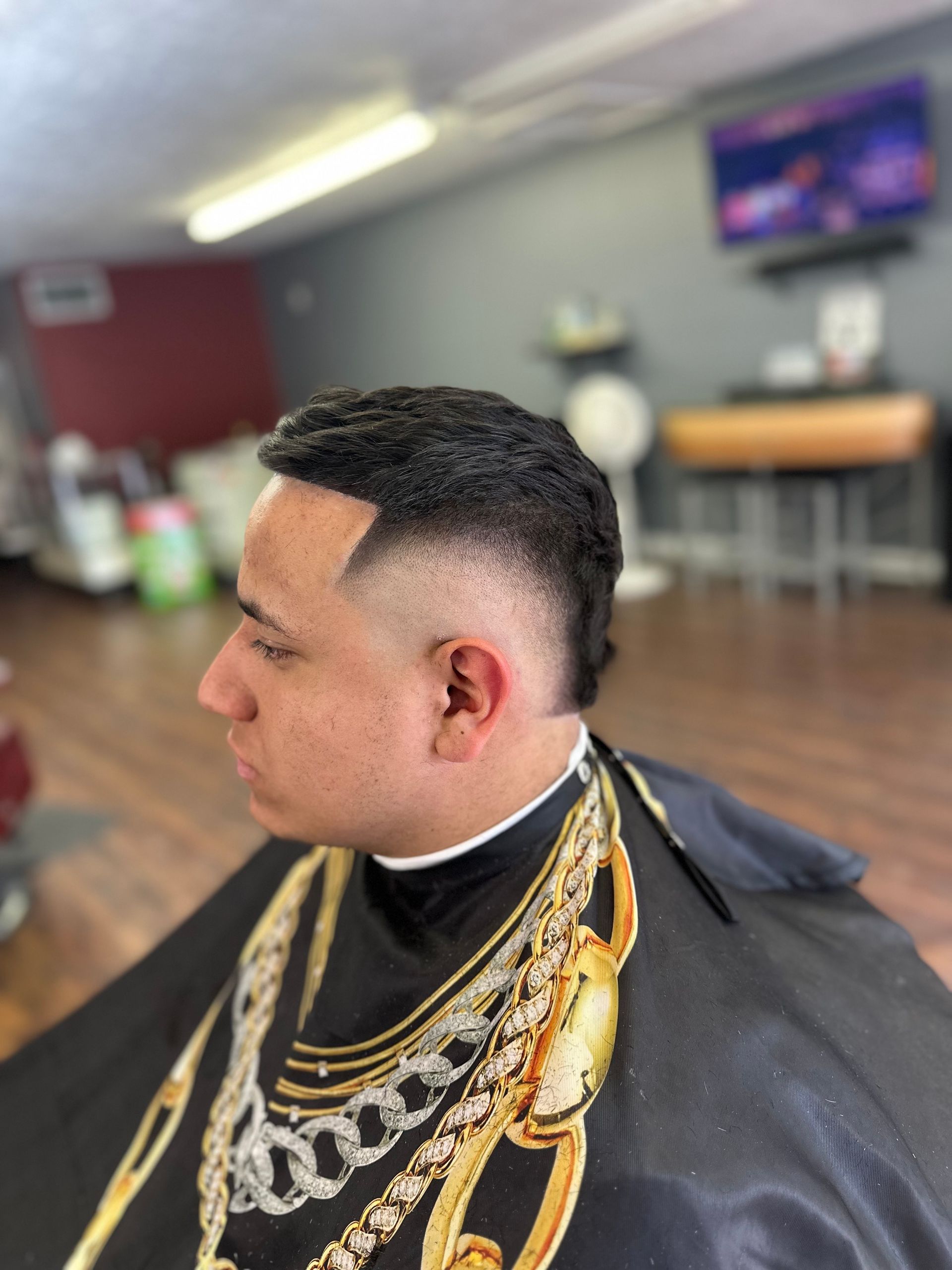 A man is getting his hair cut at a barber shop.