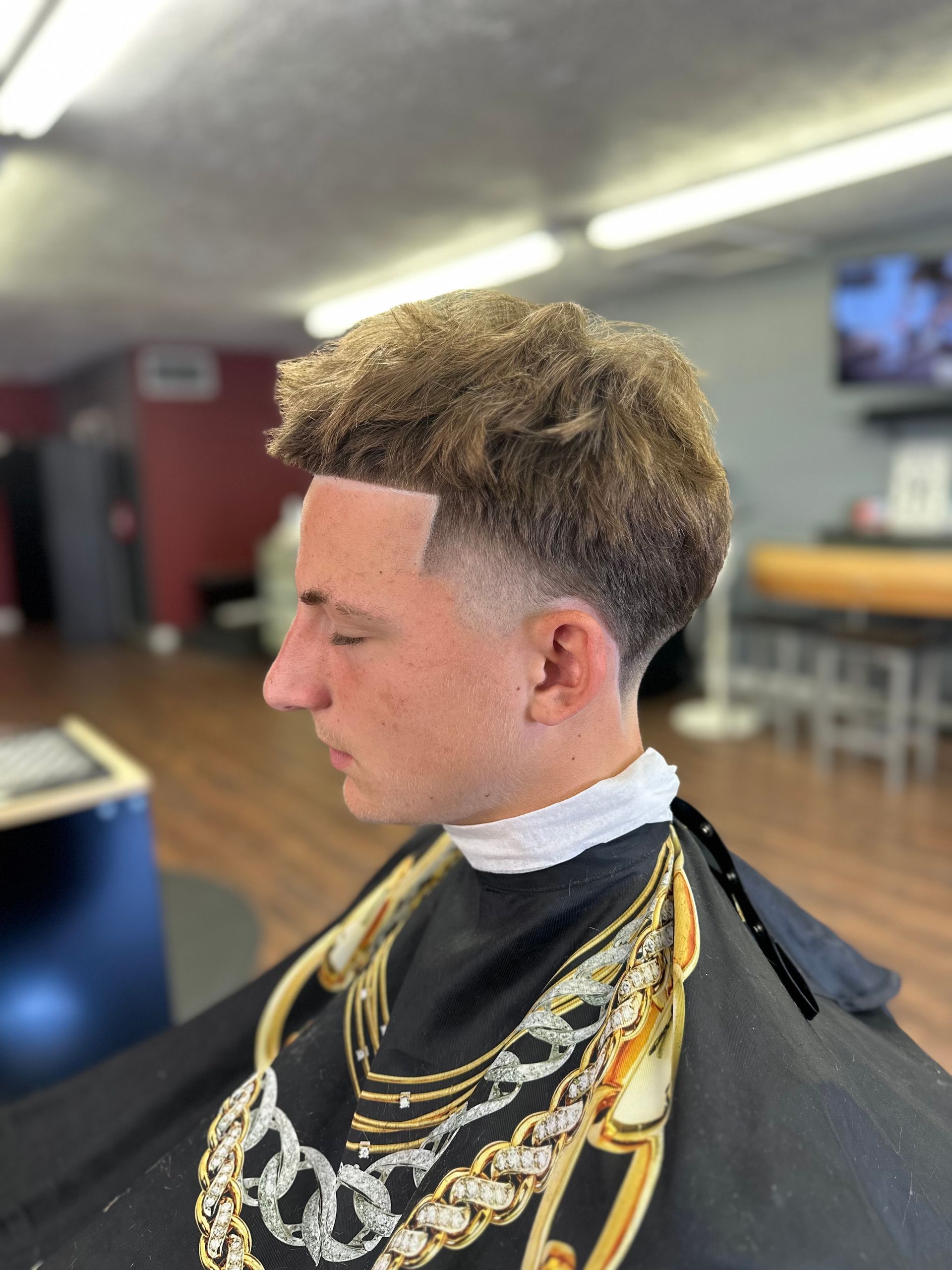 A man is getting his hair cut at a barber shop.