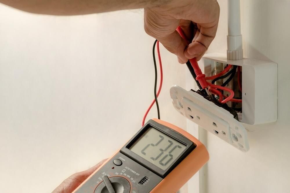 A person is using a multimeter to test a electrical outlet.