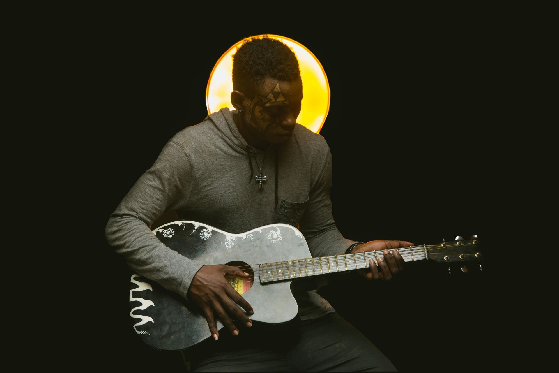 A man is playing a guitar in a dark room.