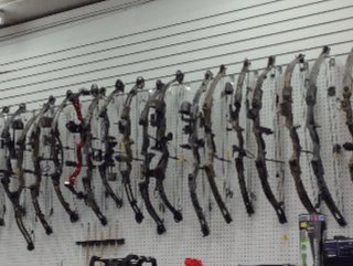 Archery bows displayed on a white wall in a store.