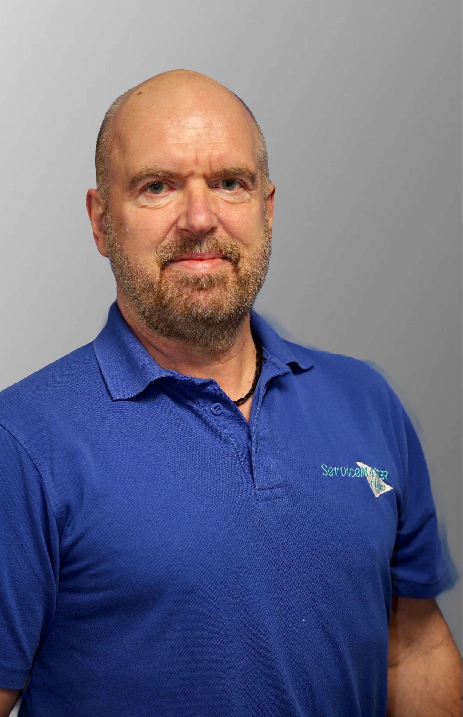 A man in a blue shirt is standing in front of a yellow van.