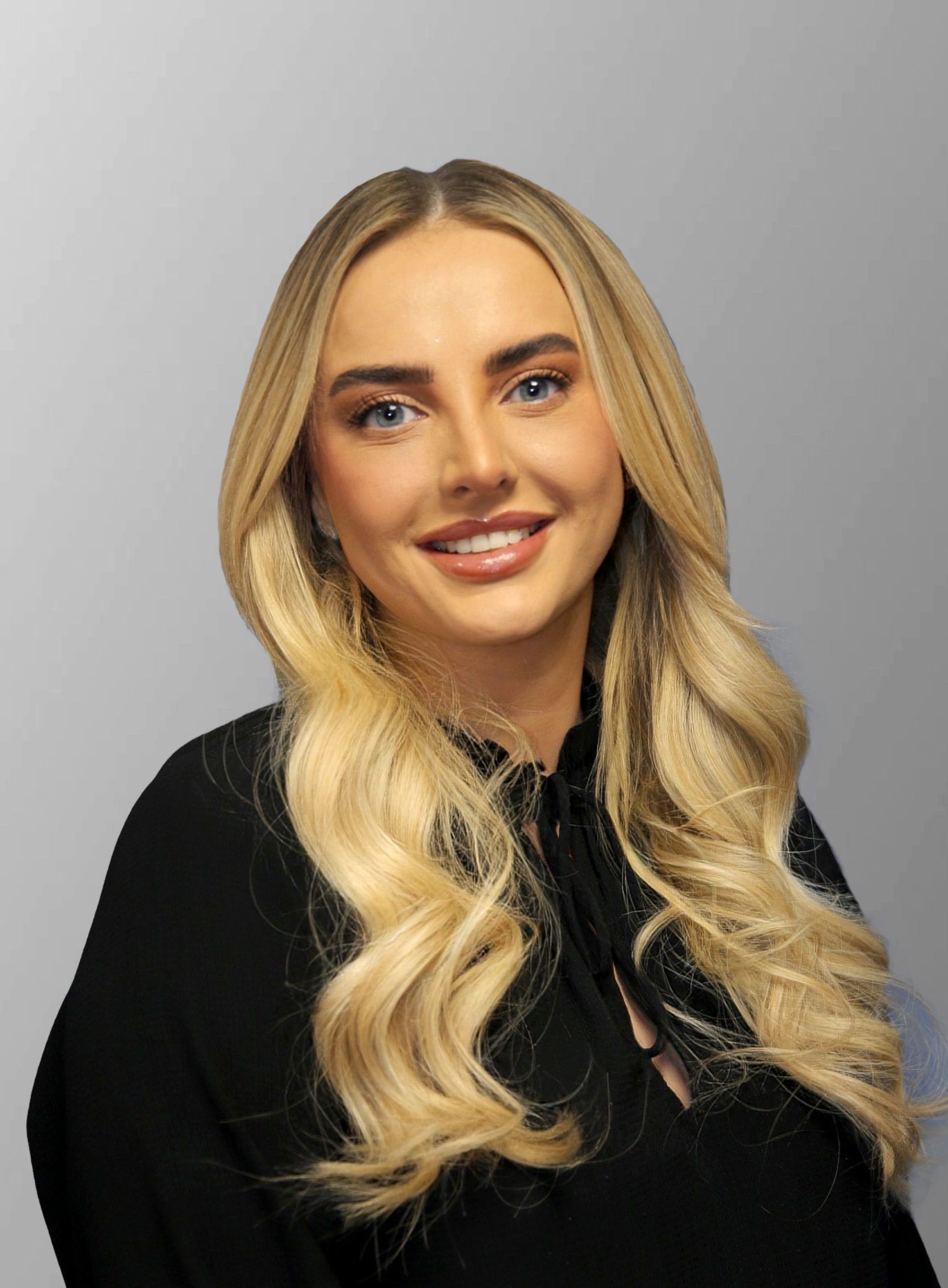 A woman is sitting in a car wearing a black jacket and a white shirt.