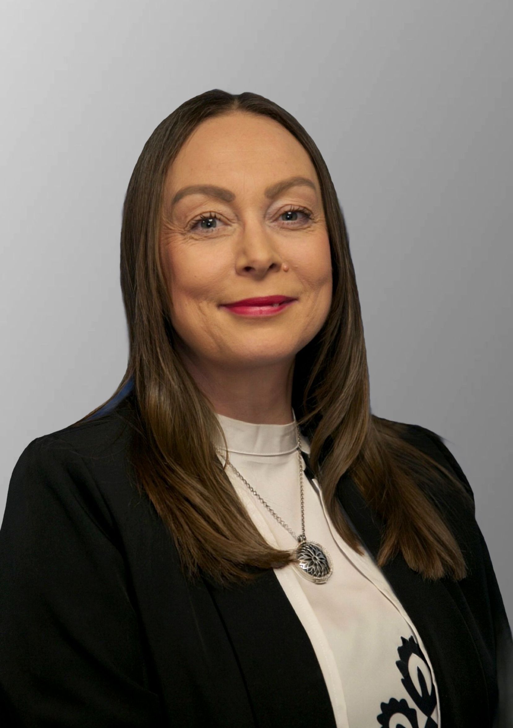 A woman in a blue jacket is smiling in front of a car
