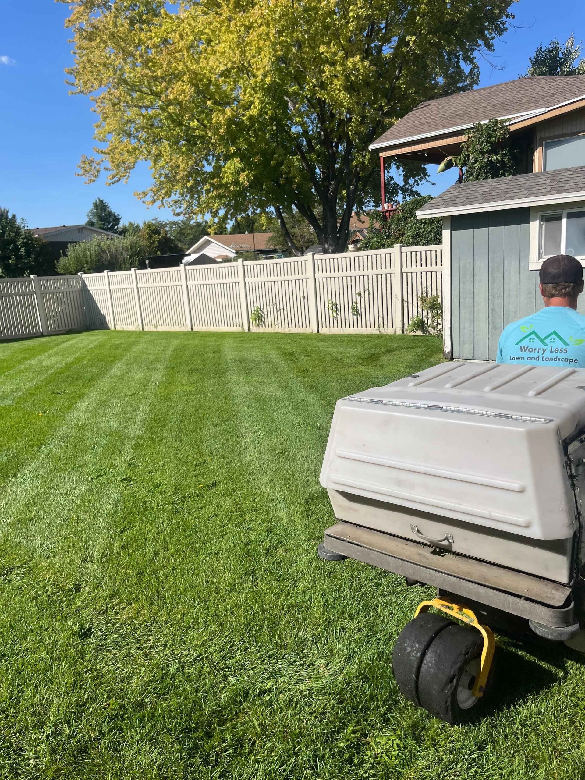 Lawn mower cutting green grass in a sunny field, spraying out clippings.