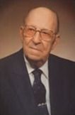 Portrait of Lawrence Tufts. Wearing glasses, wearing suit and tie, looking slightly to the side.