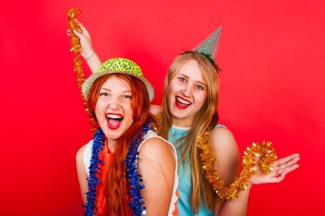 Two women celebrating at a red backdrop photo booth.